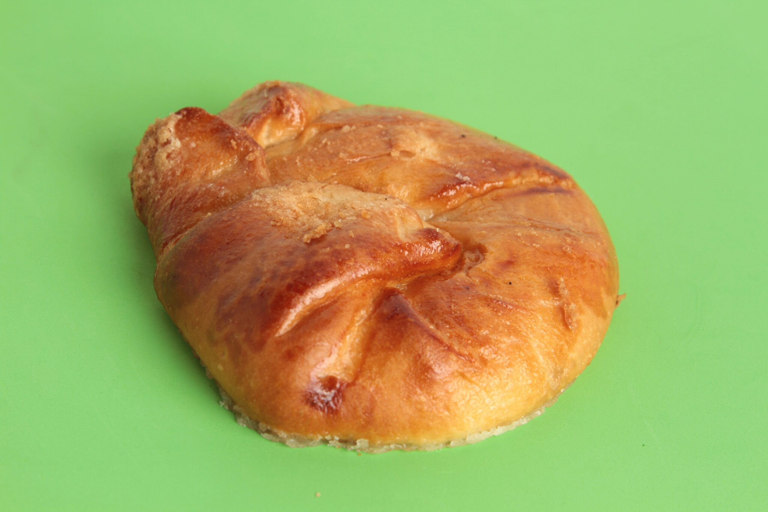 A freshly baked honeybun with a golden crust, photographed against a bright green background. Photo by Robcarbo, licensed via Depositphotos.