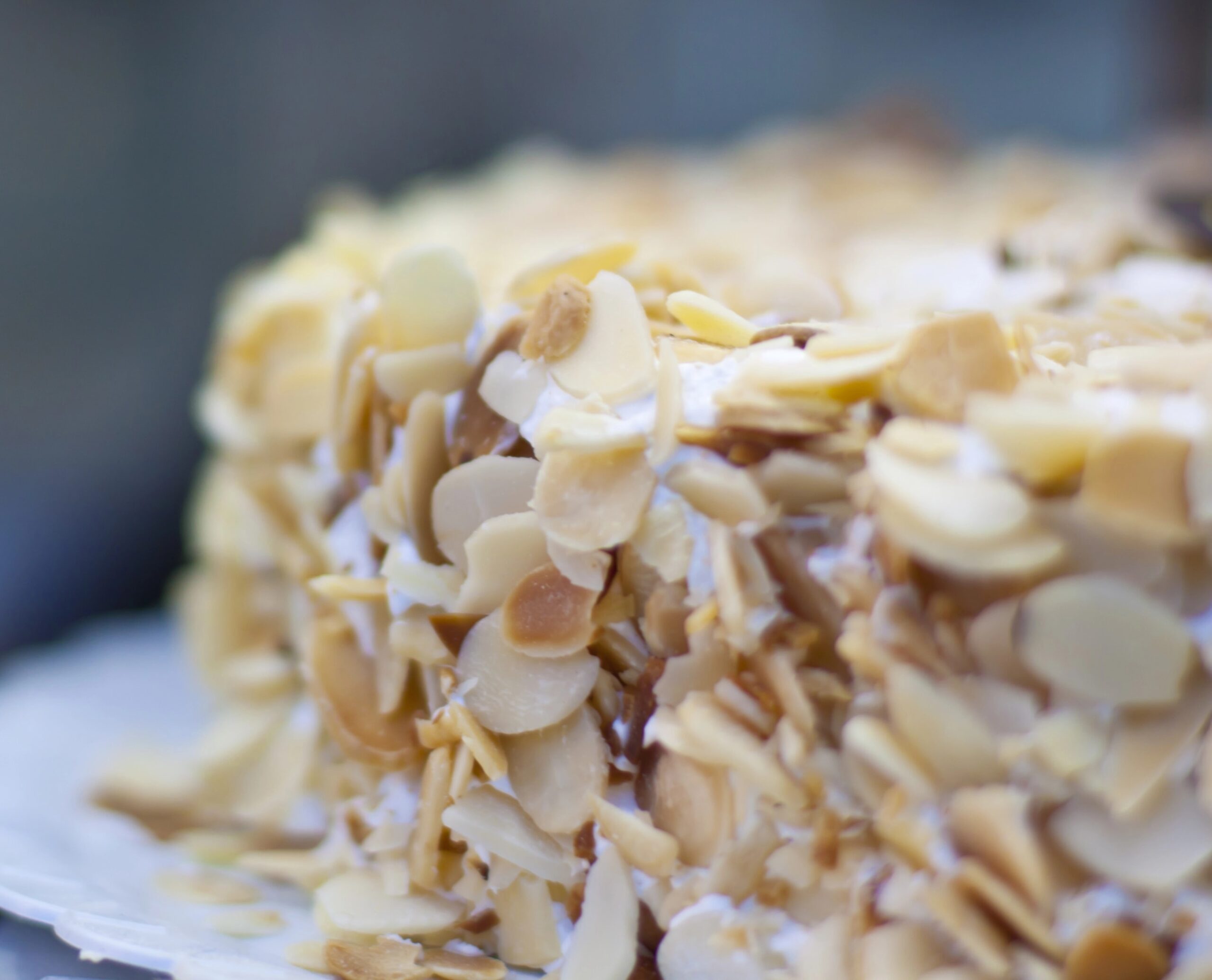 A close-up detail of an almond cake generously coated with sliced almonds, highlighting texture and topping. Photo by kasto, licensed via Depositphotos.