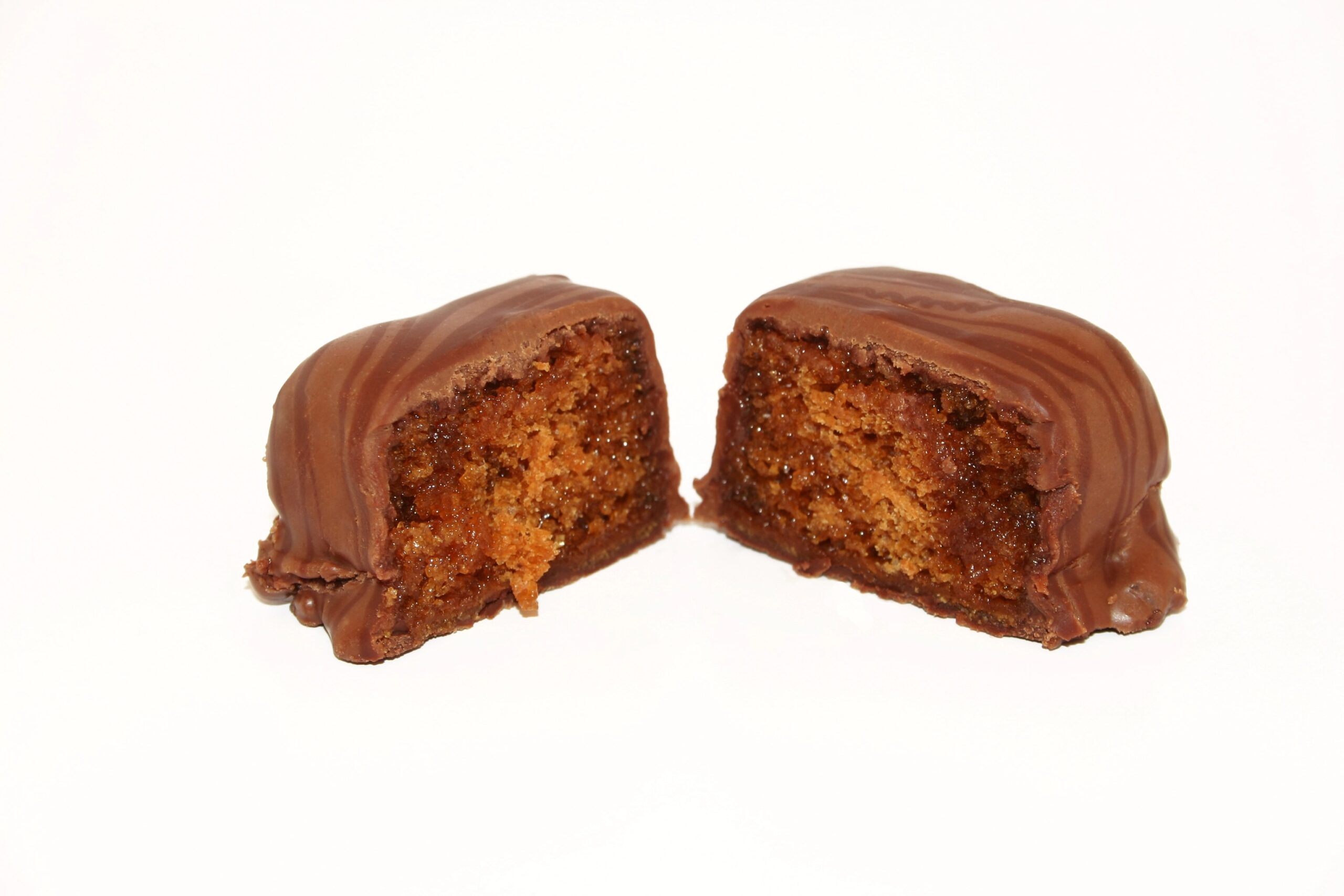 A chocolate-covered honey bun sliced in half, revealing a moist cinnamon and honey-filled interior against a white background. Photo by lucato, licensed via Depositphotos.