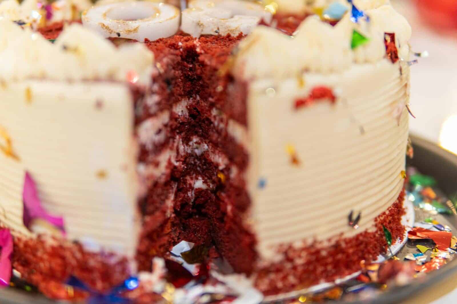 Delicious red velvet cake adorned with colorful confetti for a celebration.