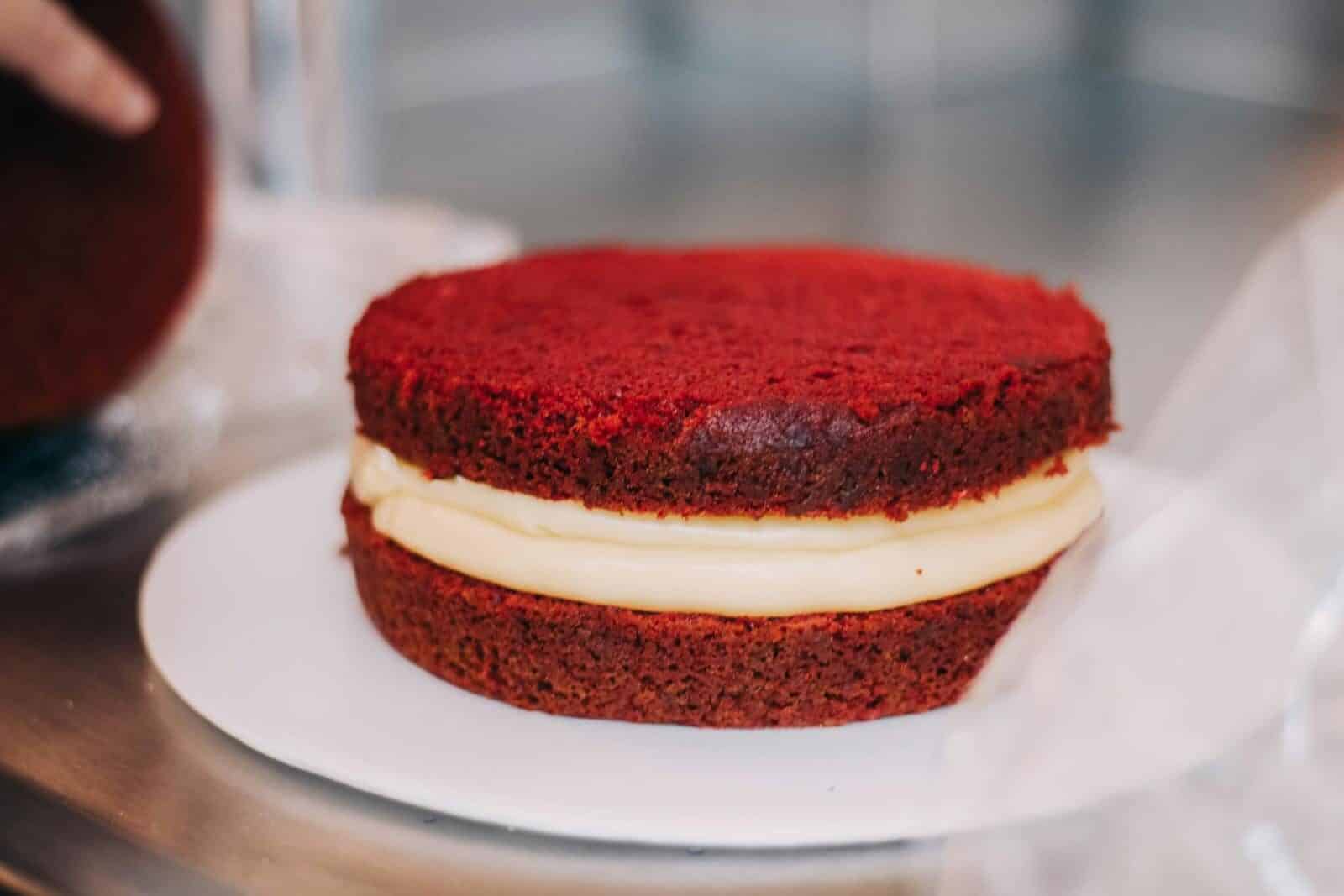 Close-up of a red velvet cake with cream filling on a white plate.