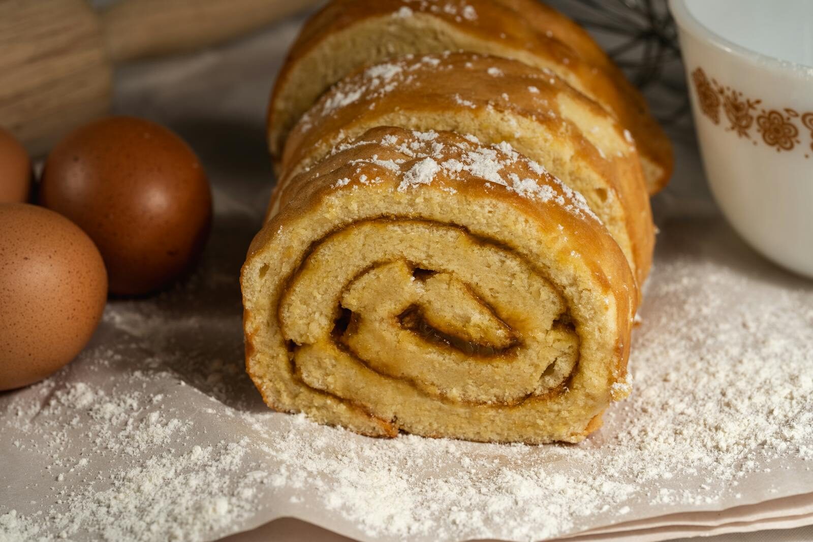 Tasty homemade Swiss roll cake surrounded by eggs and flour, perfect for baking enthusiasts.