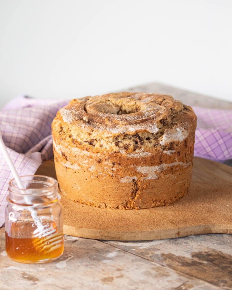 a cake sitting on top of a wooden cutting board next to a jar of honey